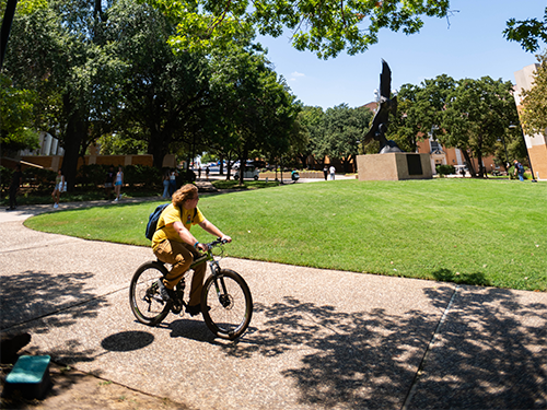 Student riding bike on campus