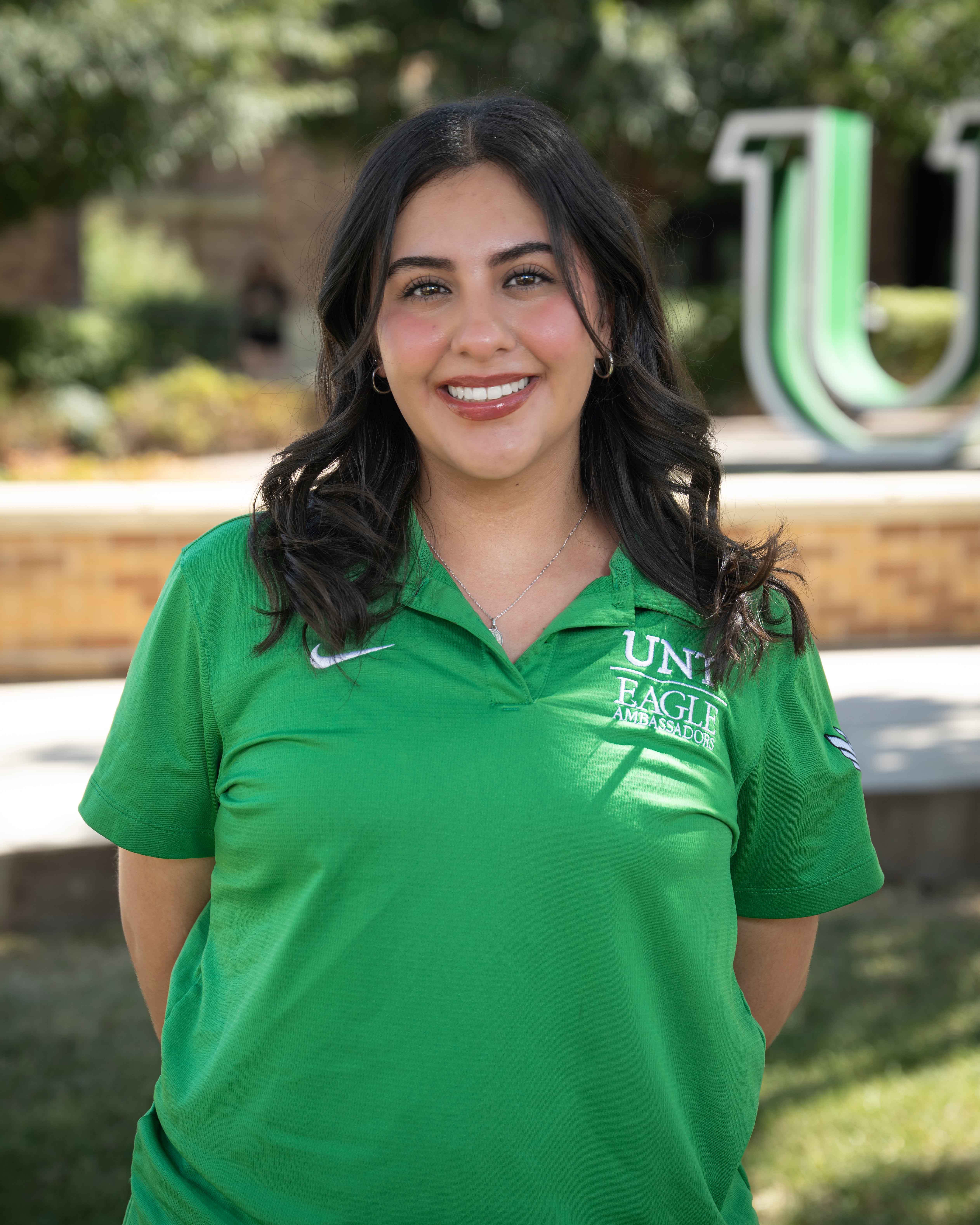 Woman smiling in front of UNT Logo