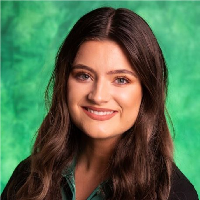 Woman smiling in front of a green background